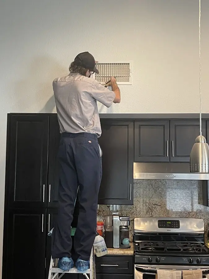 Technician inspecting an air vent during HVAC service in Toppenish